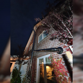 Kaminrohre außen an Backsteinfassade bei Nacht